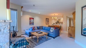 Ein Wohnzimmer mit einem blauen Sofa, einem Holztisch und einem Kamin aus Stein.
