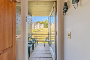 A wooden door leading to a porch with plastic chairs and a view of a residential area. - Stratton walk on/ski off, King bed, walk 2 food/drink (Stratton)