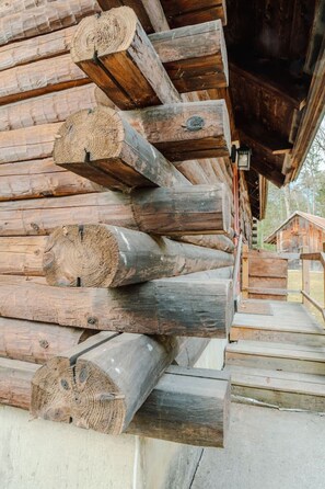 A stack of wooden logs leaning against a building with a visible staircase leading up to a door. - Stratton; 4 min. Renovated, games, fireplace! (Jamaica)