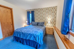 Una camera da letto con un letto, due comodini, un tavolino e una finestra con tende.