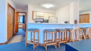 A kitchen with a central island, wooden stools, and a dining table with chairs. - Stratton walk on/off, walk to food/drink, fireplace (Stratton)
