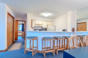 A kitchen with a central island, wooden stools, and a dining table with chairs. - Stratton walk on/off, walk to food/drink, fireplace (Stratton)