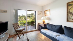 Una sala de estar con un sofá, una televisión, una silla, una mesa y una lámpara.