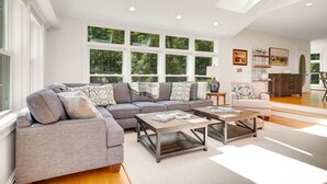 Una sala de estar moderna con un sofá modular, mesas auxiliares y amplias ventanas con vistas a zonas verdes.