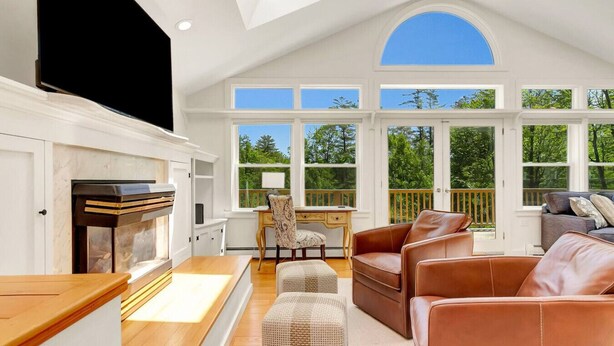 Un salón comedor espacioso con chimenea, ventanas grandes y techo alto.