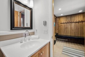 A bathroom with a white sink, a mirror with a black frame, and wooden paneling in the background. - POOL! Ski/walk on/off, King beds, Hot Tub (Stratton)