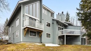 Ett modernt hus i två våningar med en balkong, ett garage och en stor trädgård.