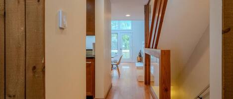 Un pasillo con suelo de madera, una escalera y vistas a una habitación con ventana.