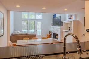 A modern kitchen with a dining table, a fireplace, and a view of the outdoors. - POOL! Ski/walk on/off, King beds, Hot Tub (Stratton)
