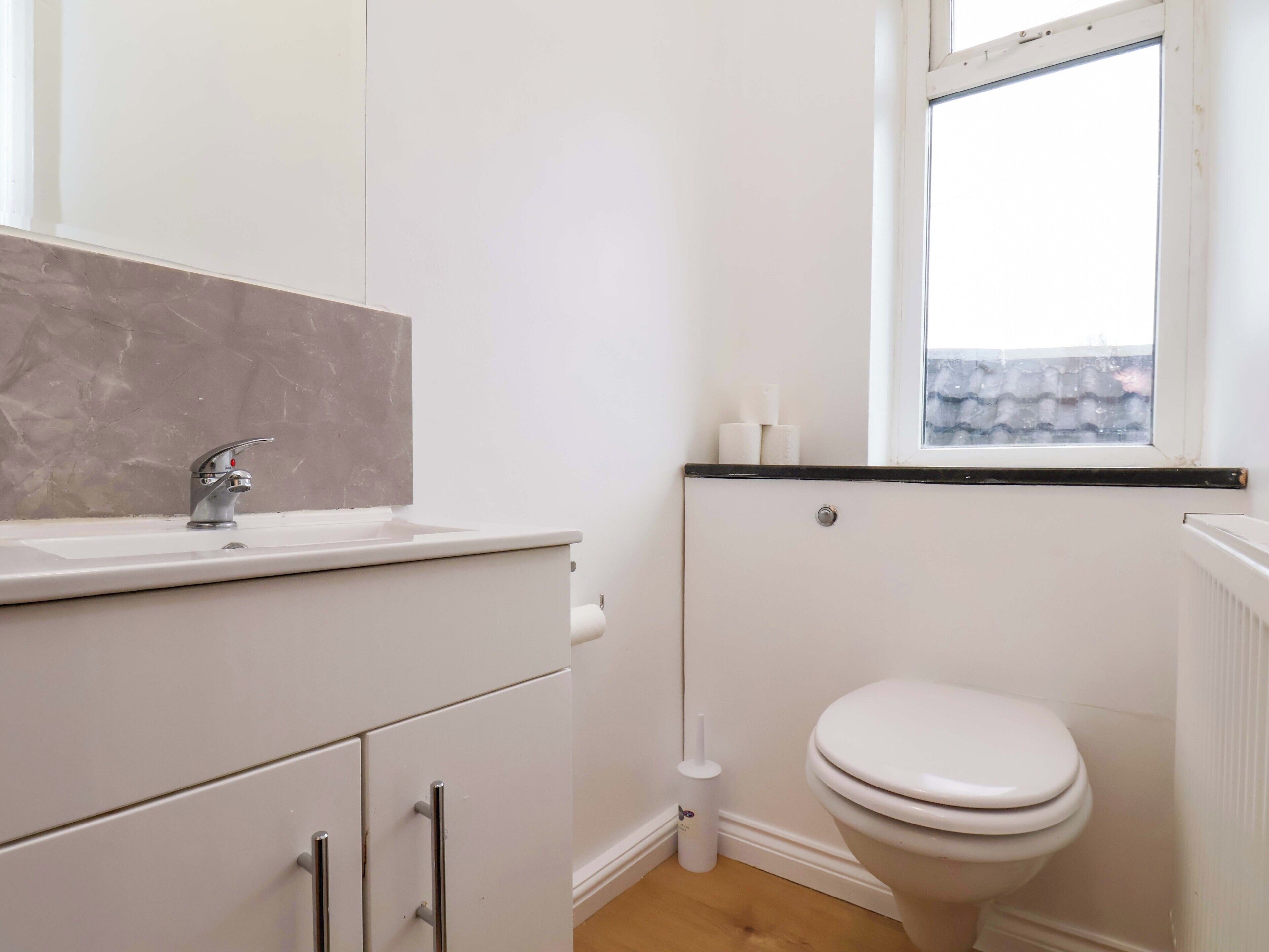 A bathroom with a white sink, a toilet, and a window.