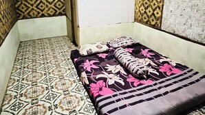 Een kamer met behang, een bed met bloemenbeddels en een plafondventilator.