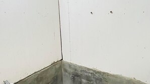 Een kleine, smalle badkamer met een toilet, een emmer en een blauwe mand.