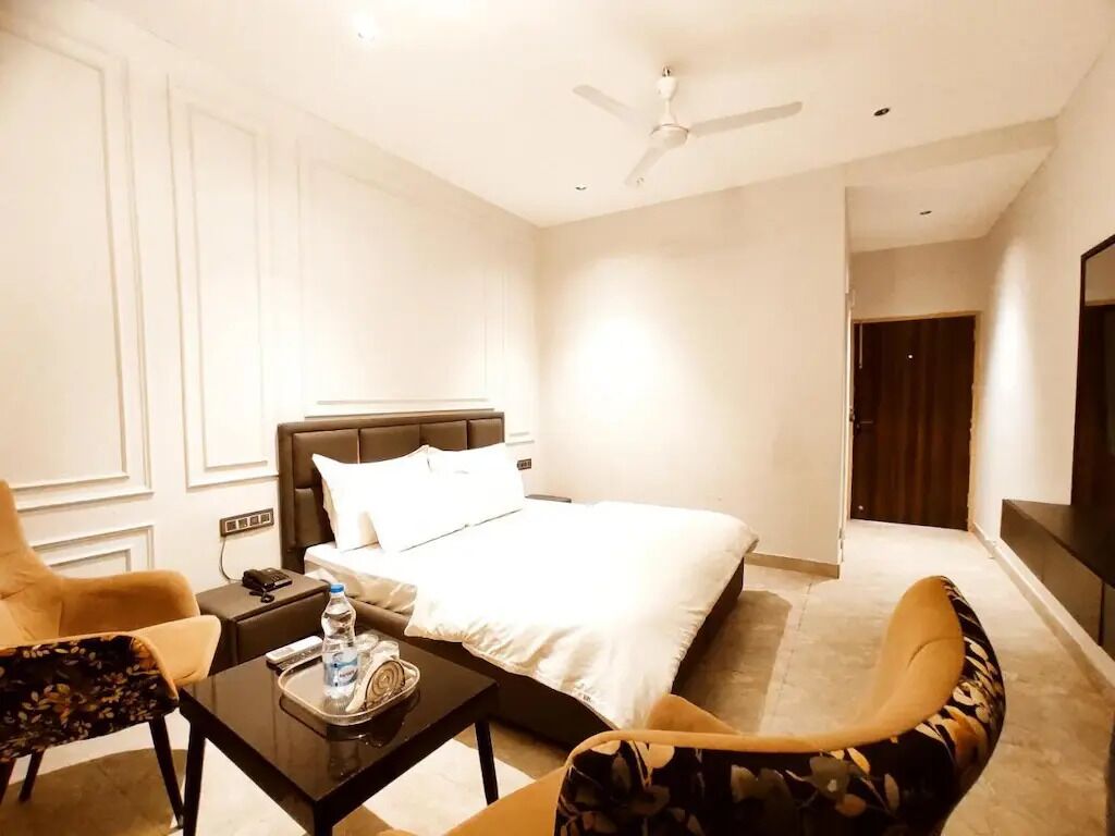 A hotel room with a bed, a desk, a chair, a TV, and a ceiling fan.