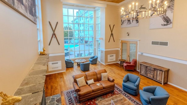A spacious living room with a large window, a chandelier, and a fireplace.