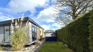 Ein modernes Haus mit großem Fenster, einem kleinen Anbau und einem gepflegten Rasen.