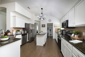 A modern kitchen with stainless steel appliances, white cabinetry, and a central island. - BULVERDE VACATION HOME (San Antonio)