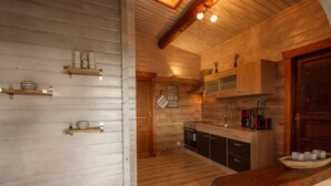 Un interno in legno con una cucina, mensole di legno e una panca.