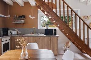 A modern kitchen with wooden cabinets, a dining table, and a view of the outdoors through a window. - Chez Cocotte 4 guests with heated pool from mid-May to September (Veuzain-sur-Loire)