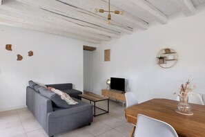 A modern living room with a grey sofa, a wooden dining table, and a TV on a wooden cabinet. - Chez Cocotte 4 guests with heated pool from mid-May to September (Veuzain-sur-Loire)