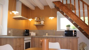 Eine Küche mit Holzausstattung, einer Kaffeemaschine, einer Mikrowelle und einer Pendelleuchte.