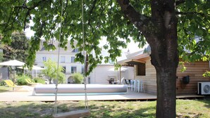 Ein Garten mit Pool, Gartenmöbeln und einem Baum.