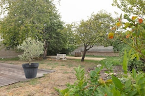 A garden with a wooden deck, a bench, and a variety of trees. - Chez Cocotte 4 guests with heated pool from mid-May to September (Veuzain-sur-Loire)