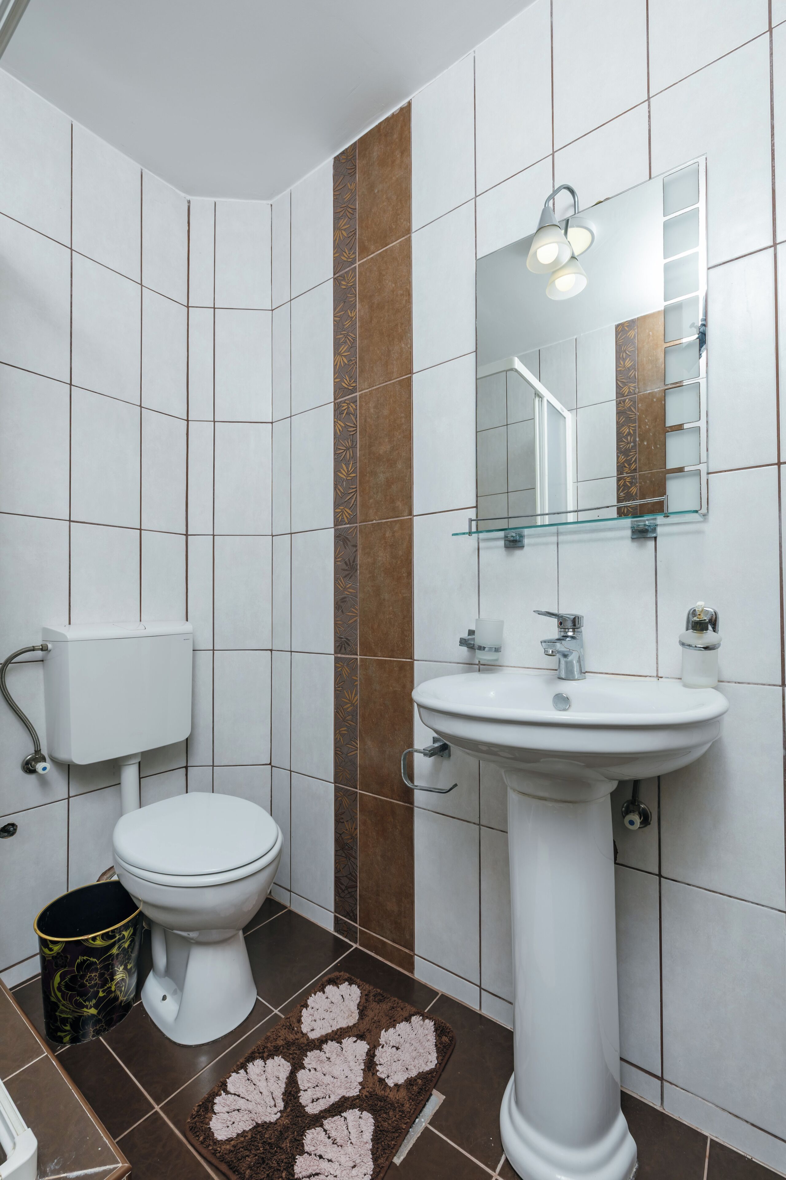 A bathroom with a toilet, sink, and mirror.