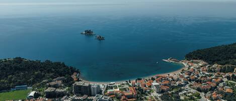 An aerial view of a coastal town with a beach, buildings, and a small island.