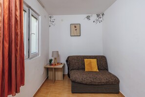 Ein Zimmer mit einer Couch, einer Lampe, einem kleinen Tisch und einem Fenster mit Vorhängen.