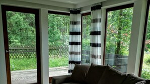 A modern living room with a sectional sofa, a wooden coffee table, and large windows with curtains.