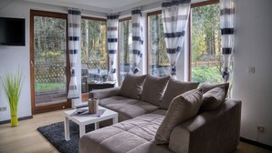 A modern living room with a sectional sofa, a small table, and a TV mounted on the wall.