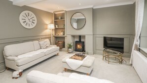 Una sala de estar con un sofá, una chimenea, un televisor y un tablero de ajedrez.