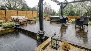 Una terraza al aire libre con jacuzzi, zona de estar y una estructura de pérgola.