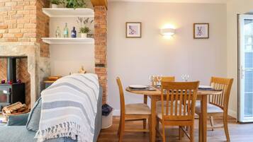 A cozy room with a brick fireplace, a dining table set for four, and two wall-mounted light fixtures.