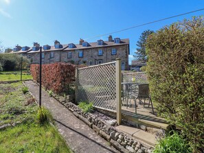 A stone building with multiple windows and a garden area with a fence and chairs. - 7 Catcliffe Cottages (Bakewell)