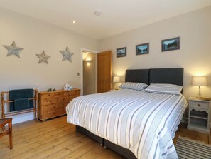 Un dormitorio con una cama grande, cómoda de madera, decoraciones con estrellas y cuadros en la pared.