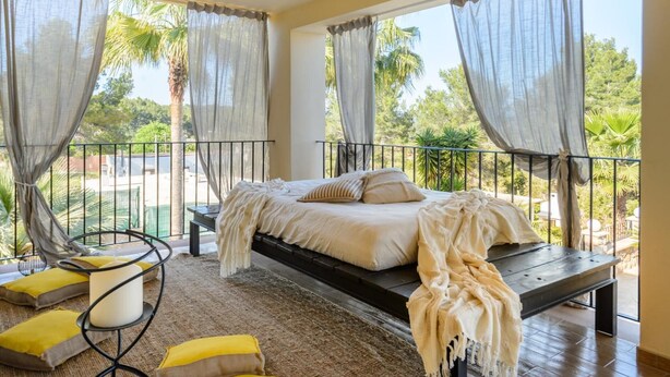 Ein Schlafzimmer mit Bett, Sitzbank, Stuhl und Blick ins Freie.