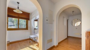 Ein Innenraum mit Holzboden, einer Bank, einem Fenster mit Jalousien, einer Tür und einem Spiegel.