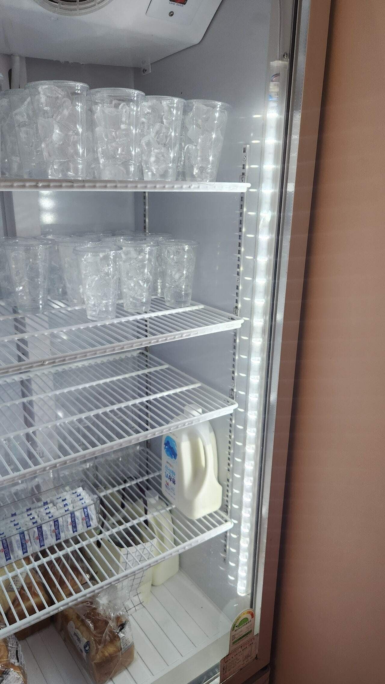Un refrigerador con varios estantes, algunos con recipientes de plástico transparente y otros con cartones de leche.