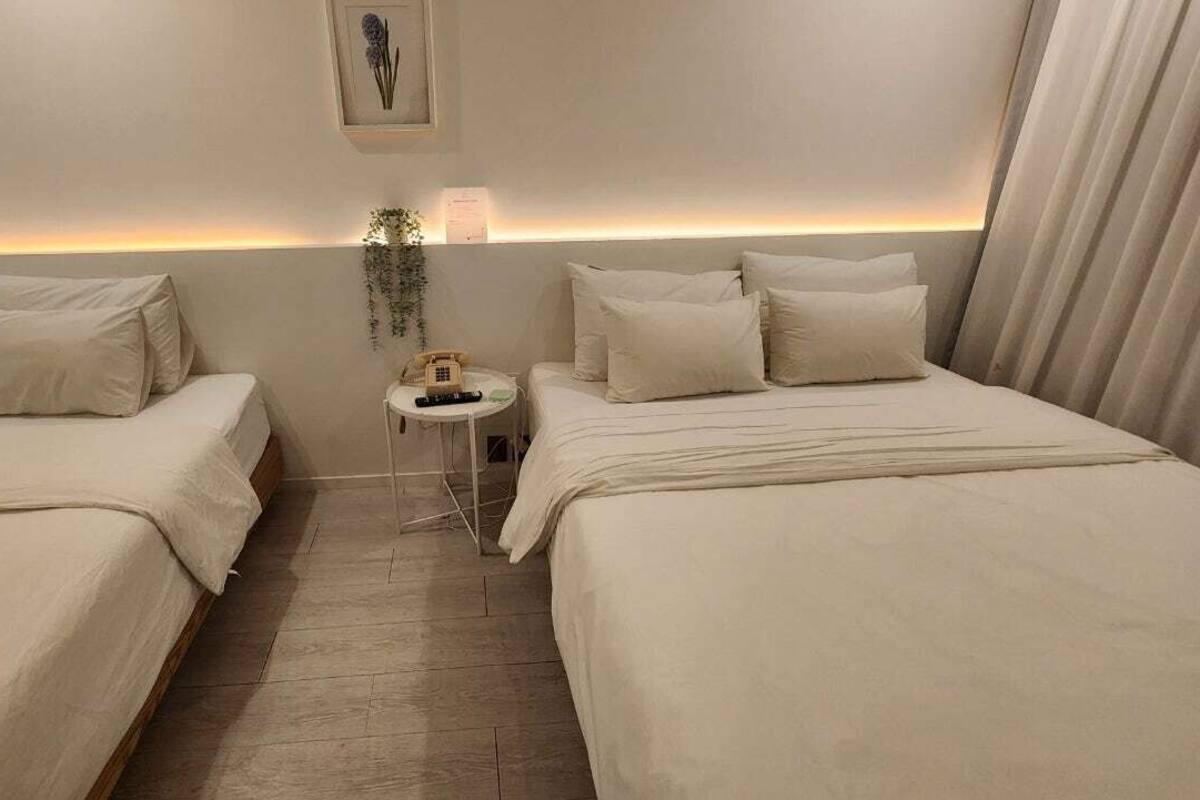 Habitació d'hotel amb dos llits, una taula petita amb un telèfon i una làmpada penjada a la paret.