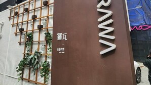 Ein Hotel Eingang mit einem großen Schild, auf dem 'HOTEL RAWA' steht, und einer Überwachungskamera darüber.