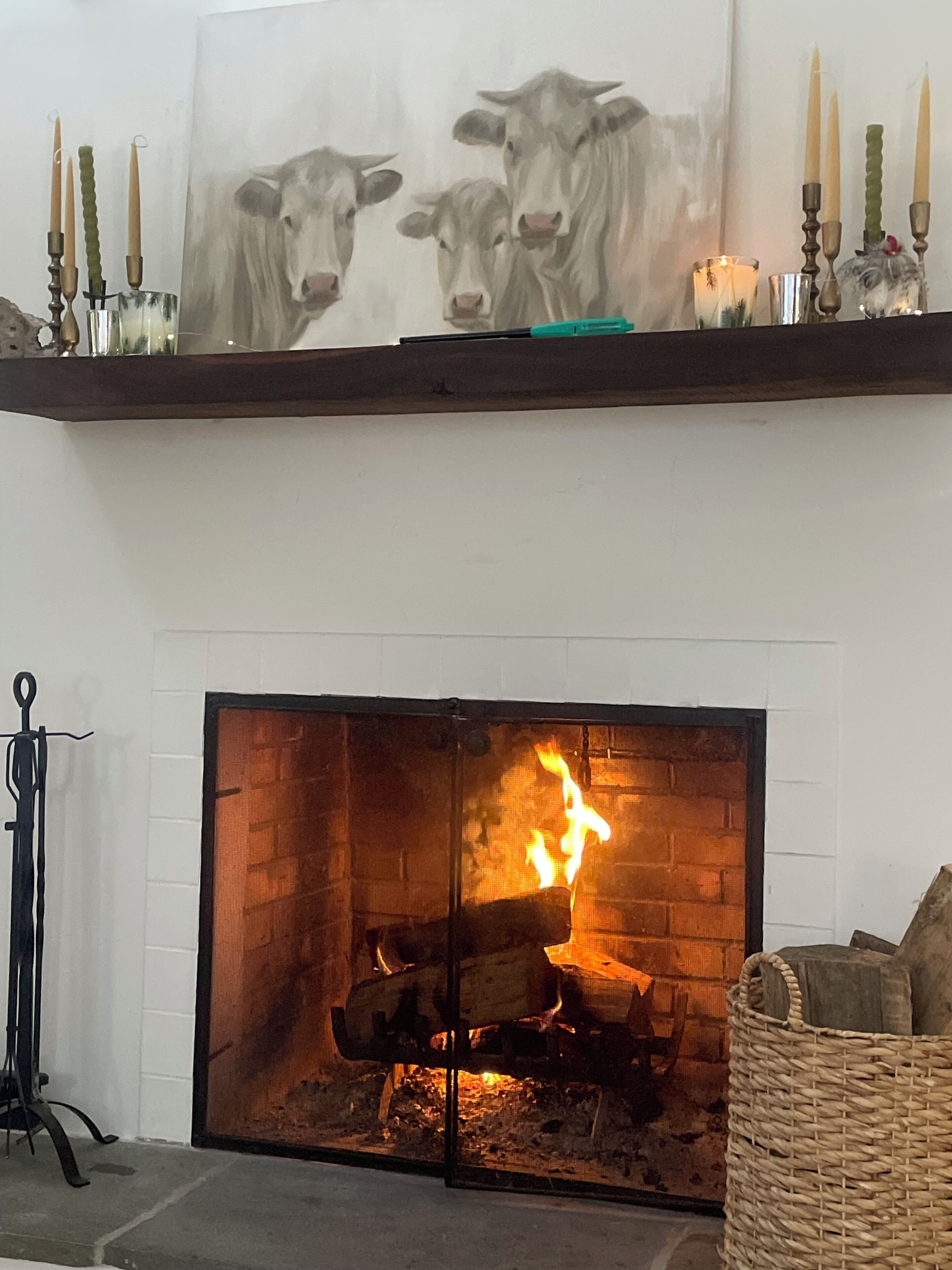 A fireplace with a burning fire, a framed artwork above it, and a candle holder with candles.