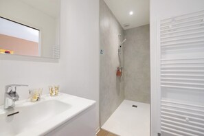 A bathroom with a white sink, two glass cups, a shower, and a white door. - Guest Room 'Envie d’ailleurs' with Shared Garden and Wi-Fi (Huisnes-sur-Mer)