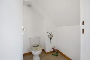 Ein Badezimmer mit Toilette, einem an der Wand befestigten Fahrradständer und einem kleinen Dekoartikel auf dem Boden.
