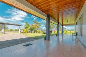 A covered outdoor area with a tiled floor, columns, and a view of the surrounding landscape. - Gray Oasis, Private Pool (La Fortuna)