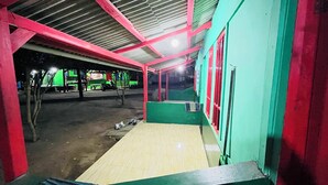 A covered outdoor area with a ramp leading to a building, a bench, and a motorcycle. - Bintang Sawarna 2 By ARBA (Bayah)
