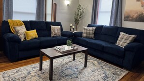 Un salon avec deux canapés bleu foncé, une table basse et un tapis à motifs.