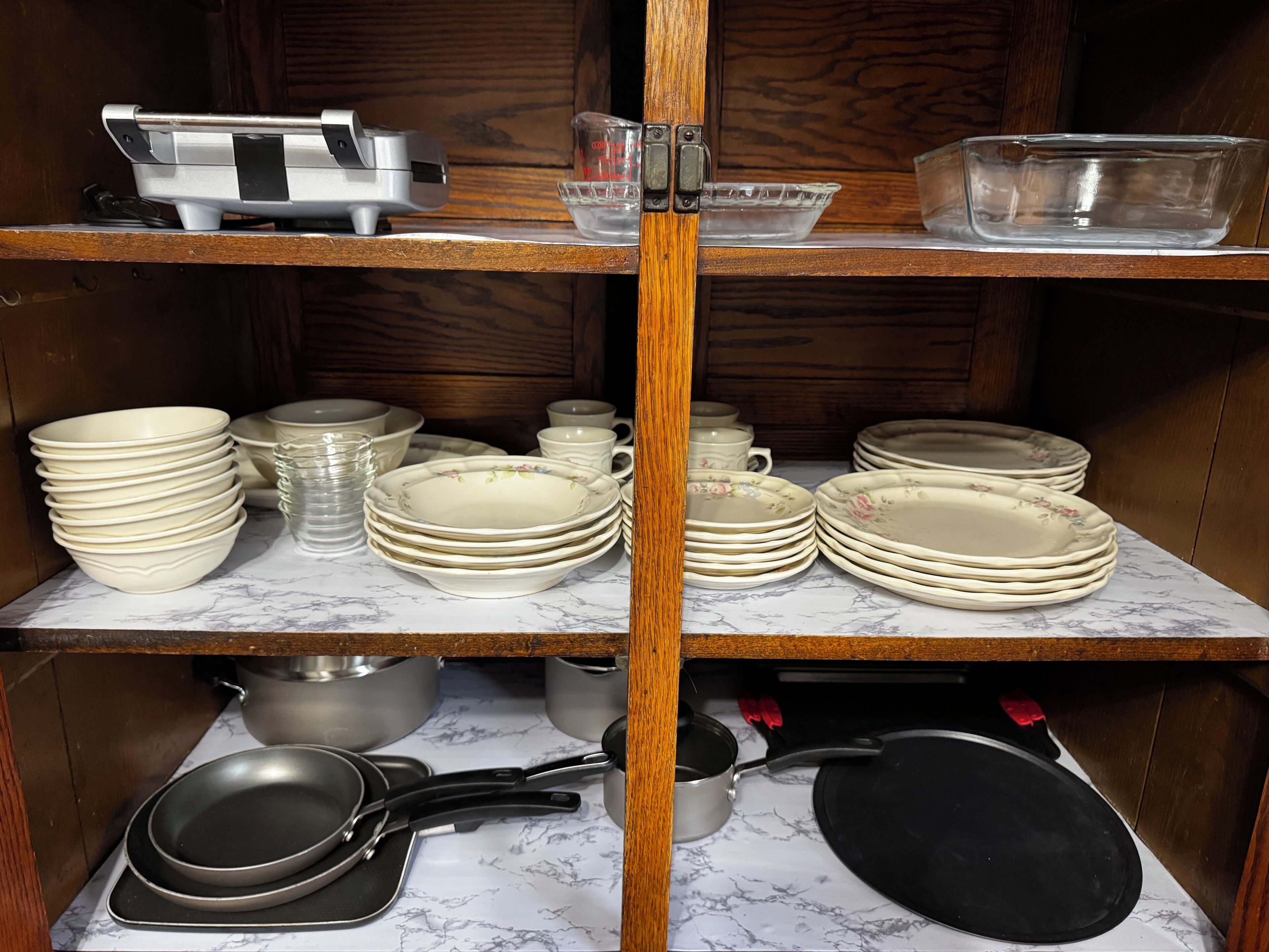 Una cocina con estantes de madera que sostienen diferentes platos y utensilios de cocina.
