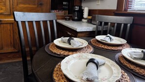 Un coin repas avec des chaises en bois, une table ronde et des sets de table en fibres tressées.