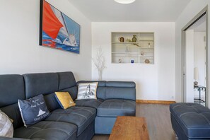 Una sala de estar con un sofá modular, una mesa de centro, un cuadro y un estante empotrado con objetos decorativos.